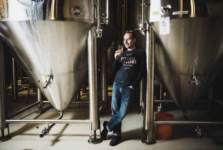 Brewmaster Iain Hill is photographed between two vertical fermentation tanks